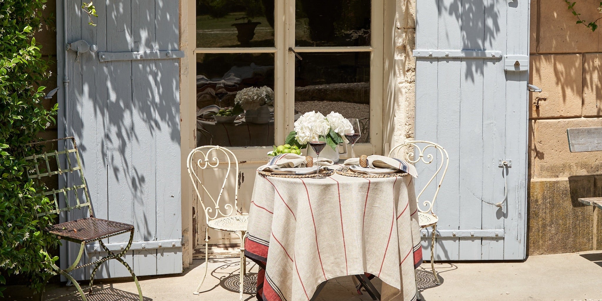 Outdoor setting with a table and chairs in front of a large wooden door with glass panels.